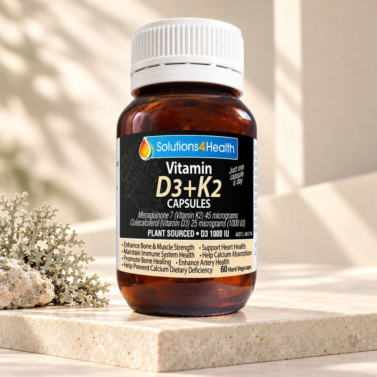 Solutions4Health Vitamin D3 + K2 60-capsule bottle beside lichen on a pale stone display.